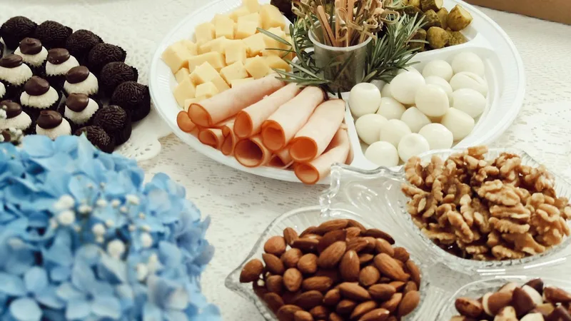 Buffet corporativo con tabla de quesos, frutos secos y pastelería para celebración laboral